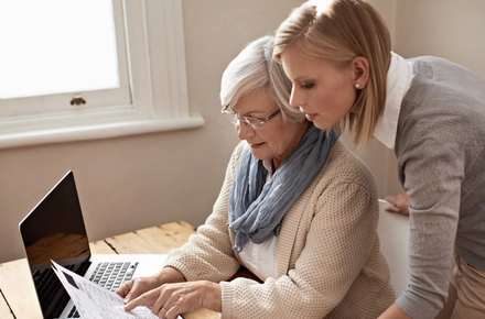 Eine Frau und ihre Mutter berechnen die Kosten für die professionelle Pflege einer älteren Person.